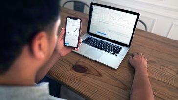 person holding iphone 6 near macbook pro