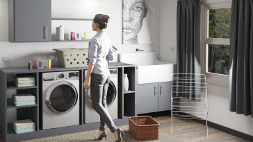 a woman standing in a laundry room next to a washer and dryer