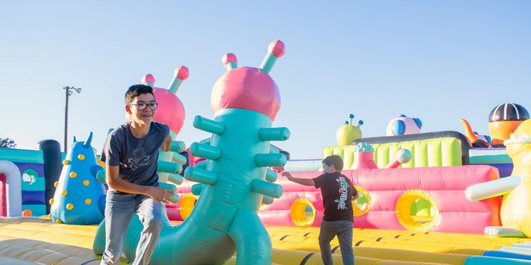 a man standing next to a giant inflatable alien