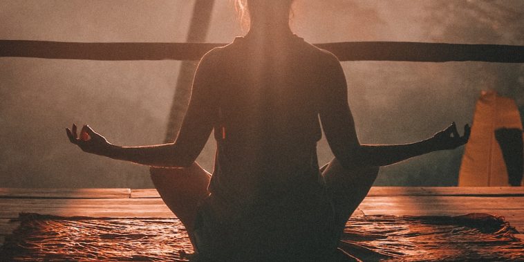 woman doing yoga meditation on brown parquet flooring