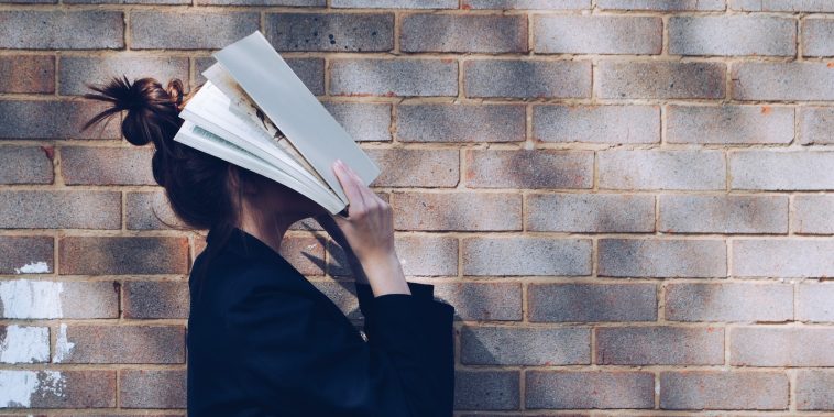 woman covering her face with white book