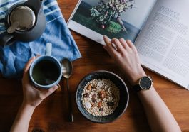 person holding blue ceramic mug and white magazine