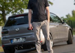 a man standing on the side of a road next to a car
