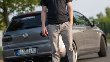 a man standing on the side of a road next to a car