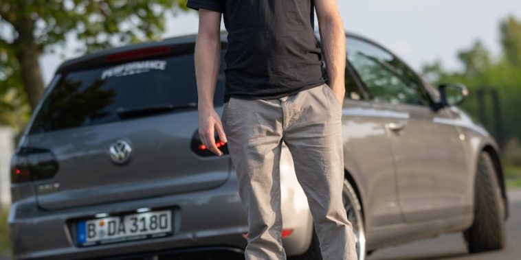 a man standing on the side of a road next to a car