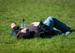 a man laying in the grass with a bottle of beer