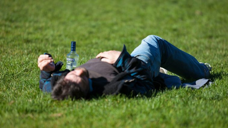 a man laying in the grass with a bottle of beer