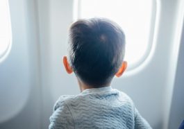 boy sitting on plane seat while viewing window