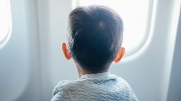 boy sitting on plane seat while viewing window