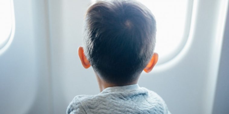 boy sitting on plane seat while viewing window