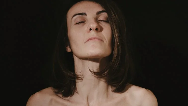 a woman with her eyes closed in the dark