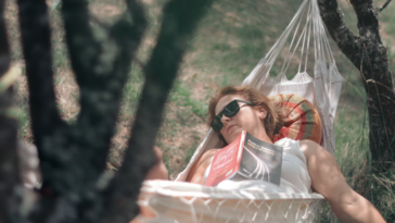 Woman relaxing in a hammock in a field on a sunny day