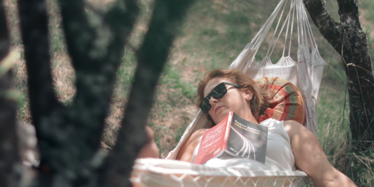 Woman relaxing in a hammock in a field on a sunny day