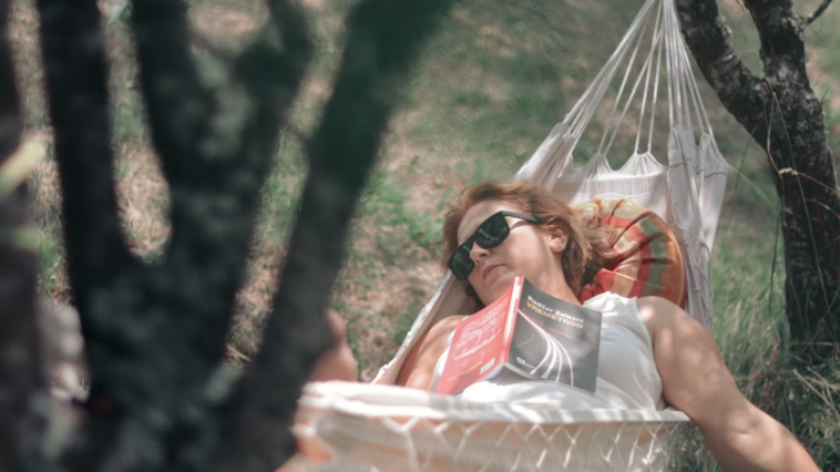Woman relaxing in a hammock in a field on a sunny day